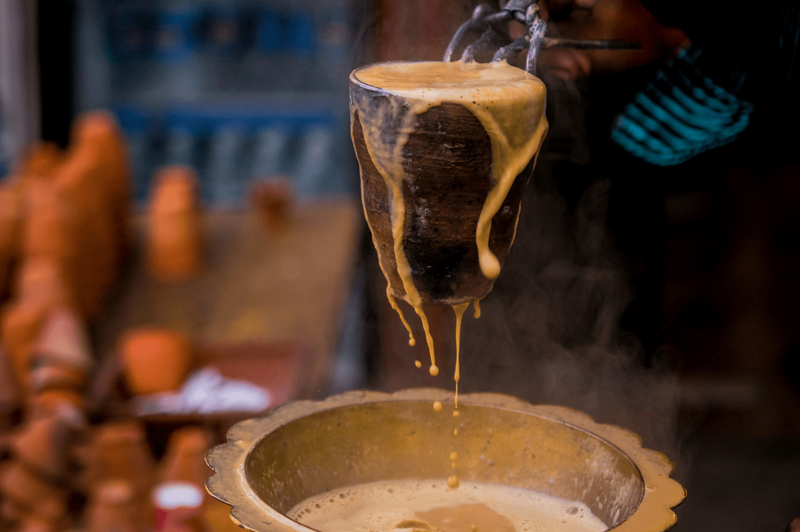 Street-style masala chai being poured into a traditional clay cup of masala chai, overflowing into a brass bowl, surrounded by whole spices like cinnamon sticks, star anise, green cardamom pods, and fennel seeds. This spiced tea blends black tea, darjeeling tea, assam tea, or green tea with fresh ginger, ground ginger, chai masala powder, tea masala, and aromatic spices from tea plantations in South India. Rooted in indian masala chai heritage, masala chai translates to traditional Indian tea brewed with milk and sugar, oat milk, or steamed milk, sweetened with brown sugar, coconut sugar, or maple syrup. Whether enjoyed as a chai tea latte, chai latte, milky tea, or milky cup, it’s a hot cup of comfort for tea drinkers and indian tea drinking culture. Made with loose tea, black tea bags, or ctc tea, this masala tea can be aerate chai for froth. Reflecting indian tea culture, tea trade, tea board standards, tea production, and tea sellers or tea vendors sourcing all the spices from south asian grocery stores, it’s served by chai vendors at tea stalls, local coffee shop, or coffee shops. Infused with fragrant spices, aromatic herbs, spice mix, and ceylon cinnamon, this cup of chai celebrates why this recipe remains a perfect cup in tea breaks, drinking tea, and review recipe traditions, prepared with spice grinder precision and ground spices from the tea plant for a rich tea brewed experience across the Indian subcontinent.