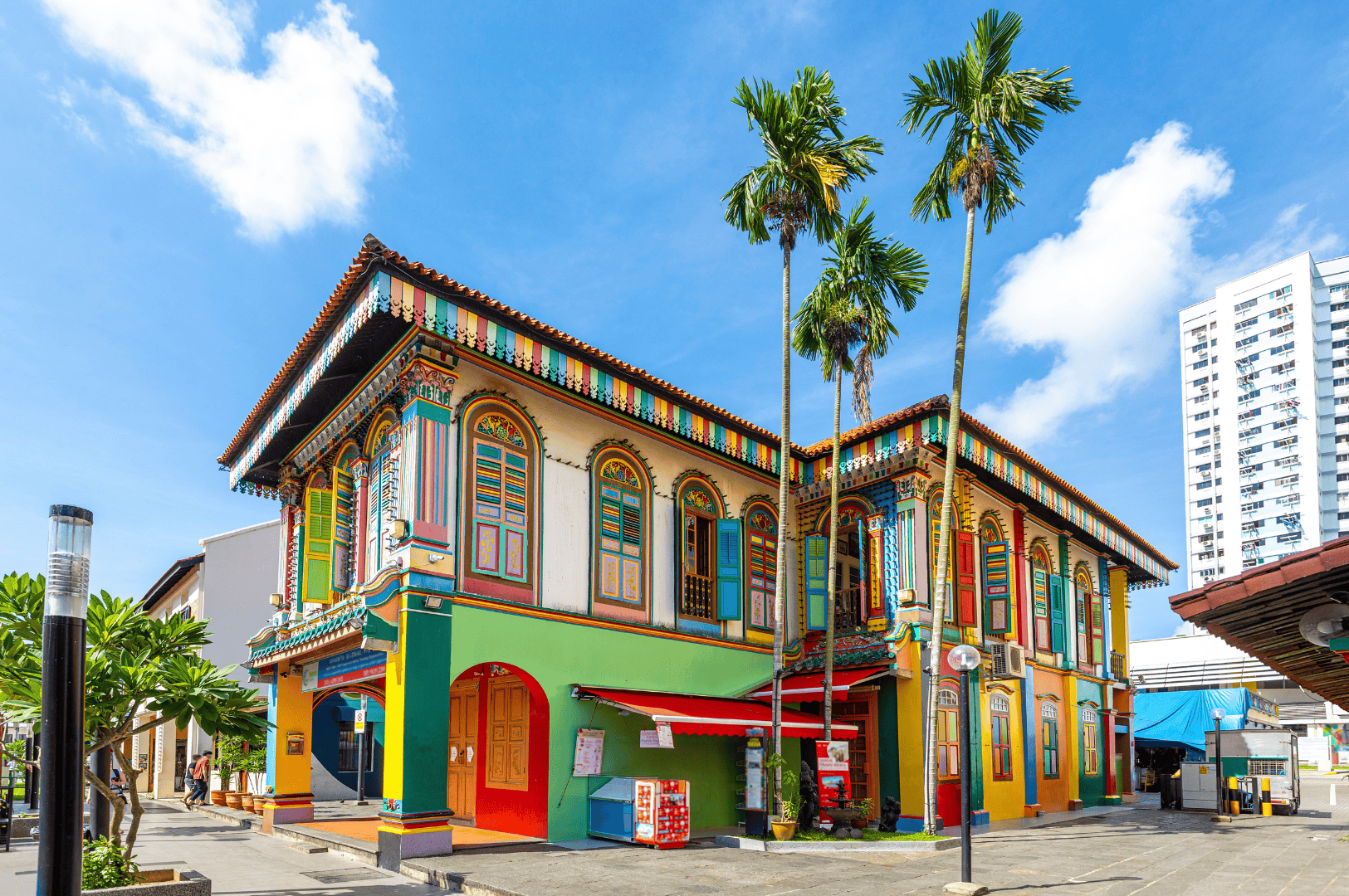 Colorful heritage building in Little India, Singapore evoking the cultural roots of masala chai and indian tea culture, where chai vendors and tea stalls serve authentic masala chai, chai tea, and chai tea latte. This scene reflects indian tea drinking traditions with tea drinkers enjoying a hot cup or milky cup of spiced tea made from black tea, darjeeling tea, assam tea, or green tea, blended with fresh ginger, ground ginger, green cardamom pods, fennel seeds, star anise, cinnamon sticks, ceylon cinnamon, and all the spices in chai masala powder or tea masala. Rooted in tea plantations of South India, masala chai translates to traditional Indian tea brewed with milk and sugar, oat milk, or steamed milk, sweetened with brown sugar, coconut sugar, or maple syrup. Whether enjoyed as a chai latte, milky tea, or cup of chai, it’s a perfect cup for tea breaks, drinking tea, or review recipe moments. Prepared with loose tea, black tea bags, or ctc tea, this masala tea is tea brewed with aromatic spices, fragrant spices, aromatic herbs, and spice mix using a spice grinder and ground spices. From local coffee shop and coffee shops to south asian grocery stores, tea vendors, tea sellers, and chai vendors, the tea trade, tea board, and tea production keep tea produced traditions alive. Inspired by why this recipe endures, this vibrant setting celebrates indian masala chai, make masala chai heritage, and the artistry of aerate chai from the tea plant to the streets.