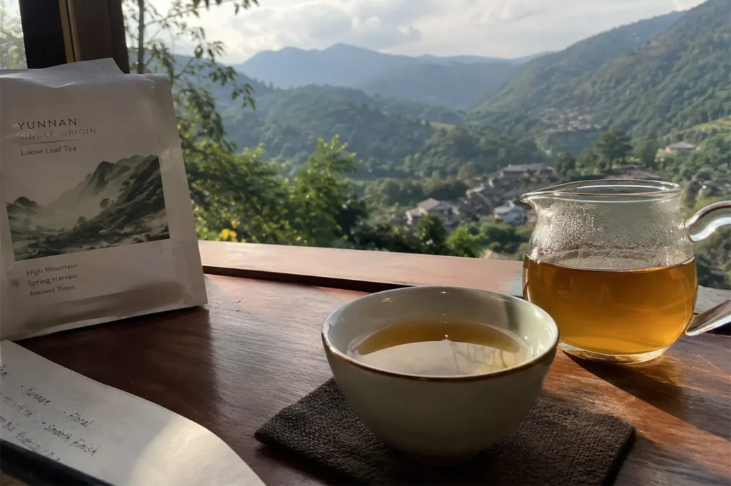 Tea tasting setup on a wooden windowsill overlooking a scenic mountain village.