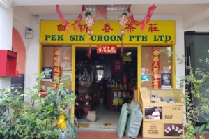 Storefront of heritage tea shop Pek Sin Choon with yellow signage and Chinese banners.