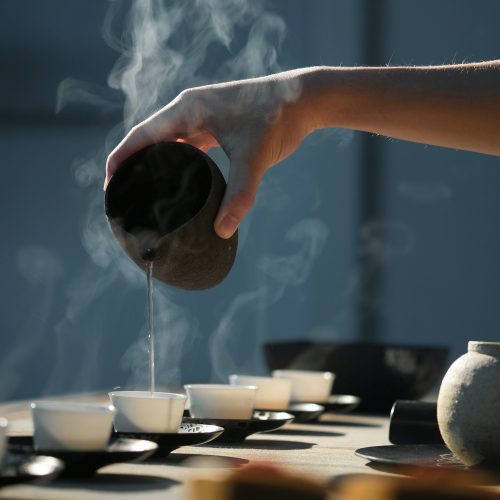 A cozy scene of someone preparing a cup of tea, with the warmth of the beverage and the texture of the wooden table evoking a sense of comfort.