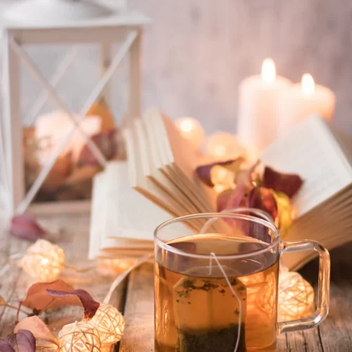 A relaxing moment captured in a cup of tea, a book, and a candle.